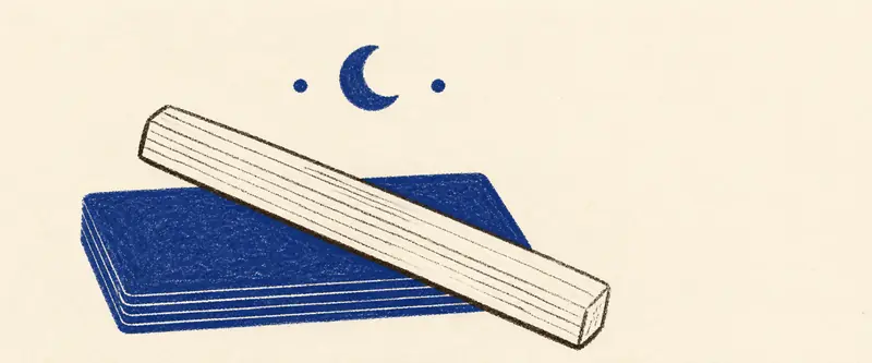 Cleansing tarot cards with selenite: a bladed selenite wand laid across a closed deck under a crescent moon