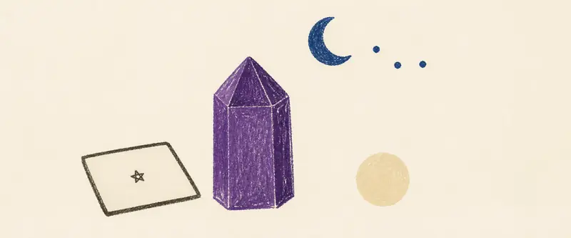 Crystals for divination: a violet amethyst point and a round pearl beside a face-down tarot card, under a crescent moon